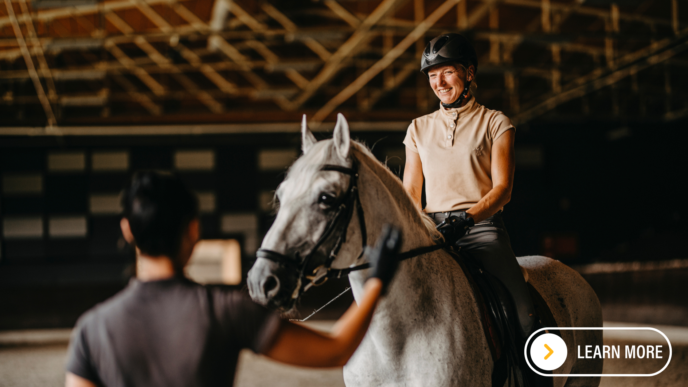 Lady riding Lipizzaner horse with an instructor guiding.